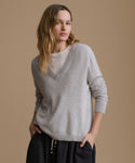 Woman wearing a gray sweater against a beige background