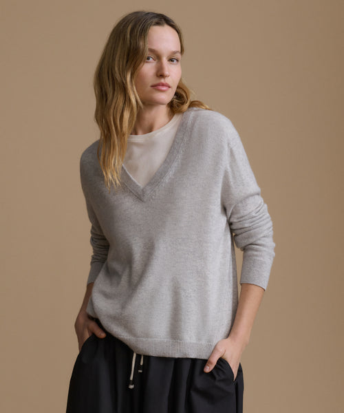 Woman wearing a gray sweater against a beige background