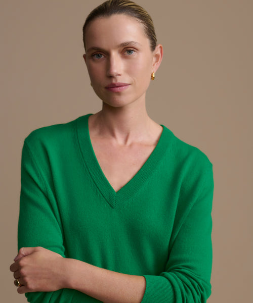 Woman wearing a green sweater against a beige background