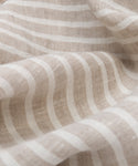 Close-up of the Frayed Linen Tablecloth, featuring white natural stripes, a soft textured weave, gentle folds, and subtle frayed edges.