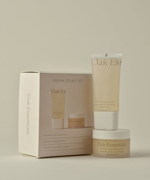 A beige Travel Fresh Start Set is displayed with a branded box, TSA-friendly body wash tube, and a jar of body scrub arranged neatly against a neutral background.