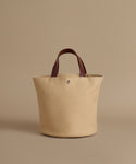 Beige tote bag with brown handles on a beige background