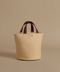 Beige tote bag with brown handles on a beige background