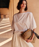 Woman holding a brown handbag against a beige wall