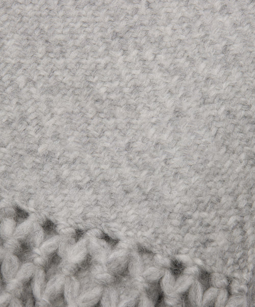 Close-up of the Glenbrook Throw shows its soft, light gray knitted fabric with a textured pattern; thicker, loosely woven stitches at the bottom highlight its cozy craftsmanship.