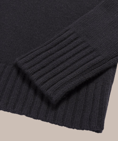 Close-up of the Grace Crewneck, a black cashmere sweater featuring ribbed cuffs and hem on a neutral background—an elegant showcase of luxury knitwear.
