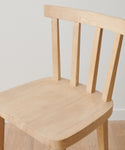 A close-up of the Hampton Counter Stool, featuring a flat seat and three vertical back slats, shown against a plain white wall on a wooden floor.