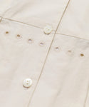 Close-up of the Harper Dress, showcasing its cream Italian cotton poplin, detailed white buttons, and horizontal rows of small embroidered eyelets that highlight its intricate stitching and texture.