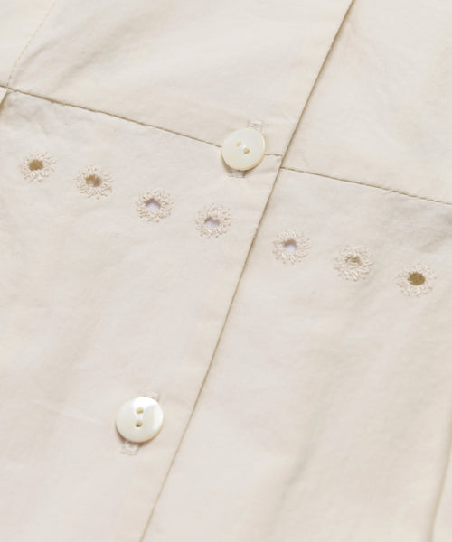 Close-up of the Harper Dress, showcasing its cream Italian cotton poplin, detailed white buttons, and horizontal rows of small embroidered eyelets that highlight its intricate stitching and texture.
