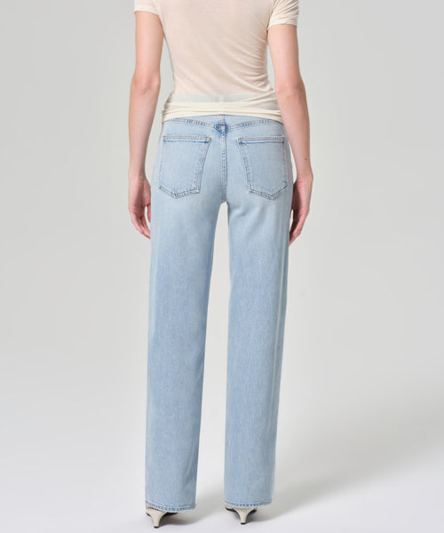 A person wearing a short-sleeved beige top and the Harper Jean—light blue, high-waisted, wide-leg jeans—is shown from the back against a plain light gray background.