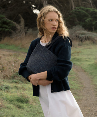 Woman holding a navy hollis bag outdoors in a natural setting