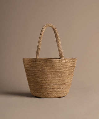 Woven straw tote bag on a beige background