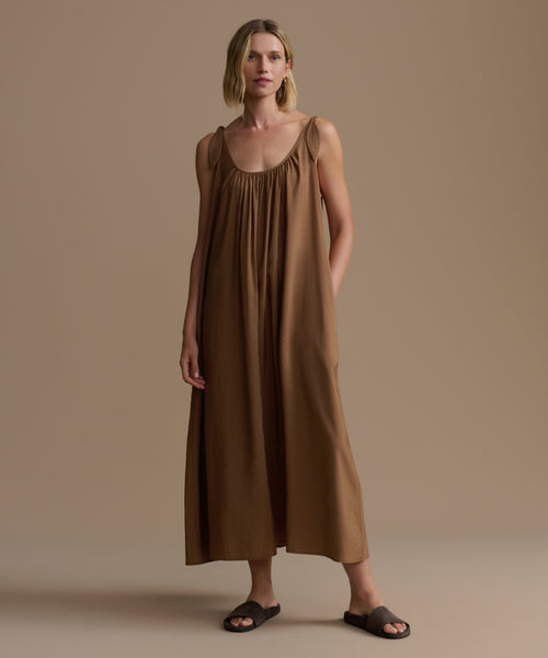 Woman wearing a brown dress against a beige background