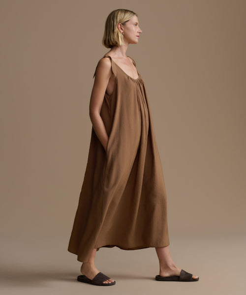 Woman wearing a brown dress against a beige background