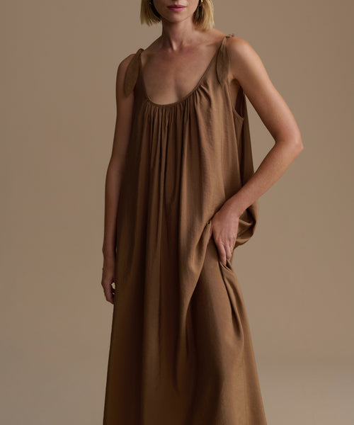 Woman wearing a brown dress against a  background