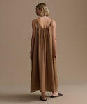 Woman wearing a long brown dress against a beige background