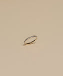 The Iris Eternity Band is a slim 14k solid gold ring featuring small, evenly spaced conflict-free diamonds around the band, shown against a simple beige background.