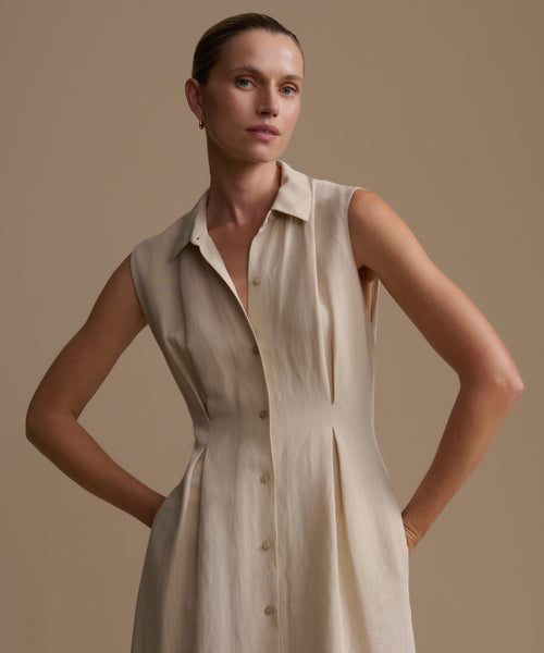 Woman wearing a beige sleeveless dress against a plain background
