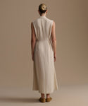 Woman wearing a beige sleeveless dress against a plain background