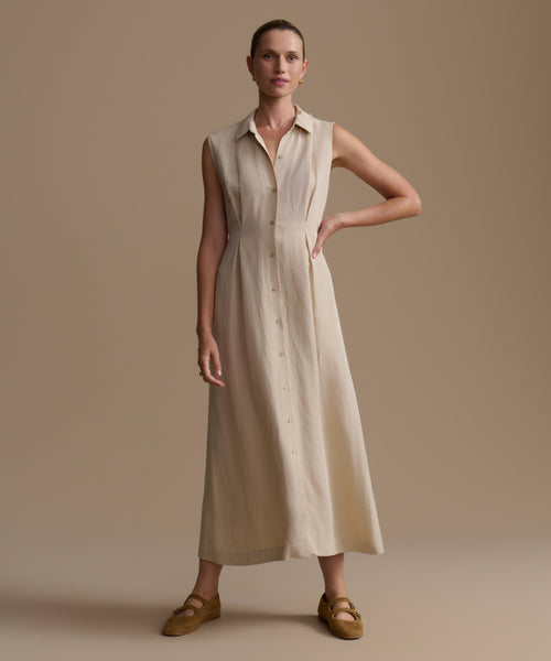 Woman wearing a beige sleeveless dress against a plain background