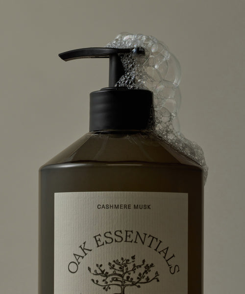 Bottle of Oak Essentials Cashmere Musk soap with a pump and visible label on a beige background