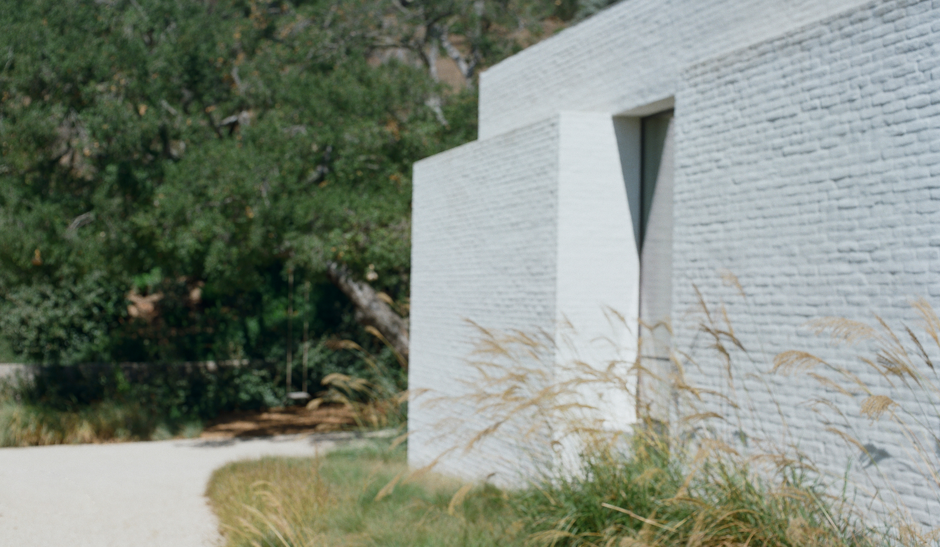 Modern building with a textured white facade surrounded by greenery