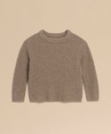 A Kids' Cashmere Fisherman sweater in beige, featuring long sleeves, ribbed knit, and a crew neckline, is laid flat on a light tan background.
