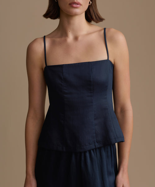 Woman wearing a navy kinney cami against a beige background