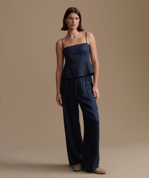 Woman wearing a navy kinney cami and pants against a beige background