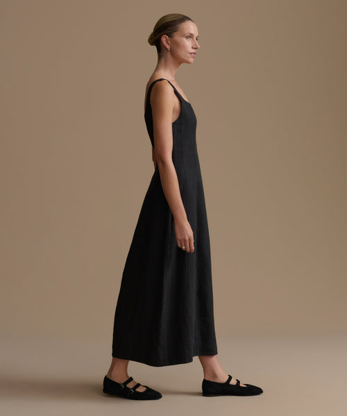 Woman wearing a black sleeveless dress against a beige background