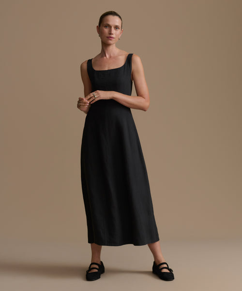 Woman wearing a black sleeveless dress against a beige background