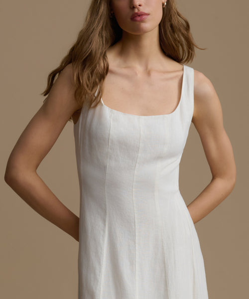 Woman wearing a white sleeveless dress against a beige background