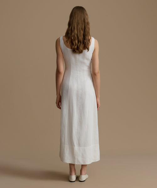 Woman wearing a white dress against a beige background