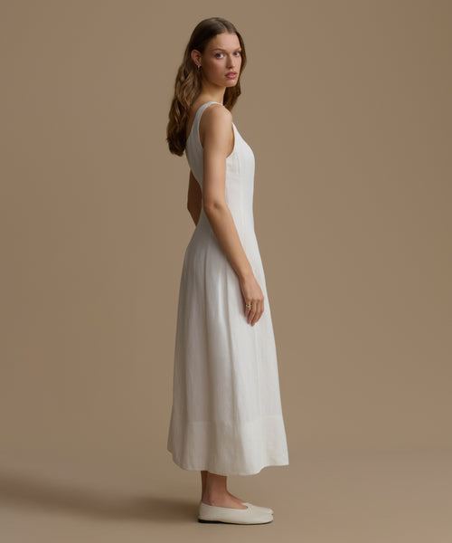 Woman wearing a white dress with cut-out back on a beige background