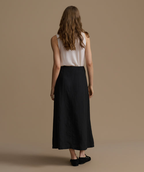 Woman wearing a white top and black skirt on a beige background