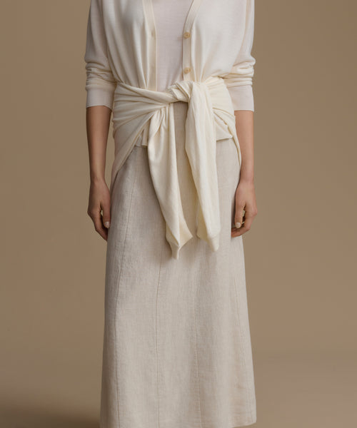 Person wearing a cream-colored outfit with a tied top against a beige background