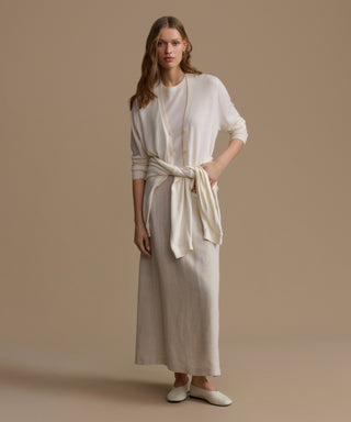 Woman wearing a beige dress with a white cardigan on a beige background