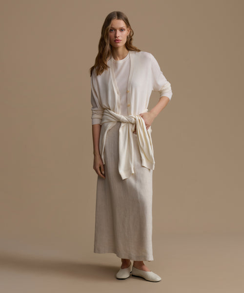 Woman wearing a beige dress with a white cardigan on a beige background