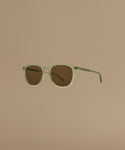 Sunglasses with a green frame and brown lenses on a beige background