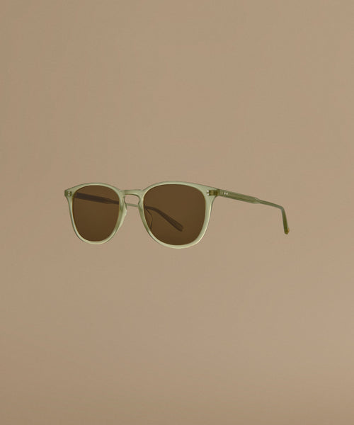 Sunglasses with a green frame and brown lenses on a beige background
