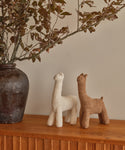 A pair of Knit Llamas on a shelf—ideal as a cuddly companion or playful decor.