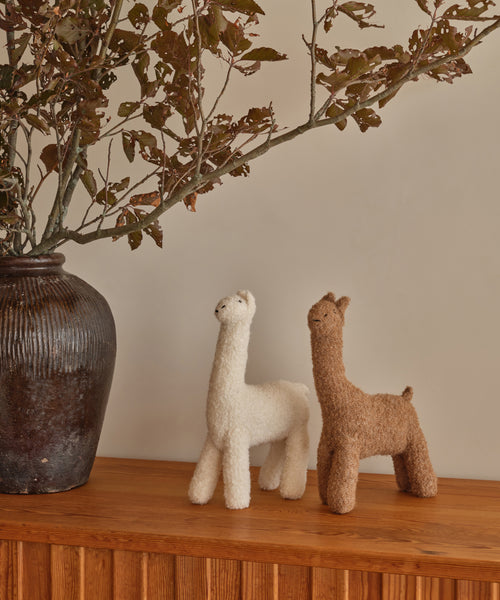 A pair of Knit Llamas on a shelf—ideal as a cuddly companion or playful decor.
