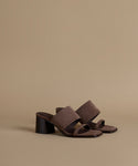 Brown sandals with a black block heel on a beige background