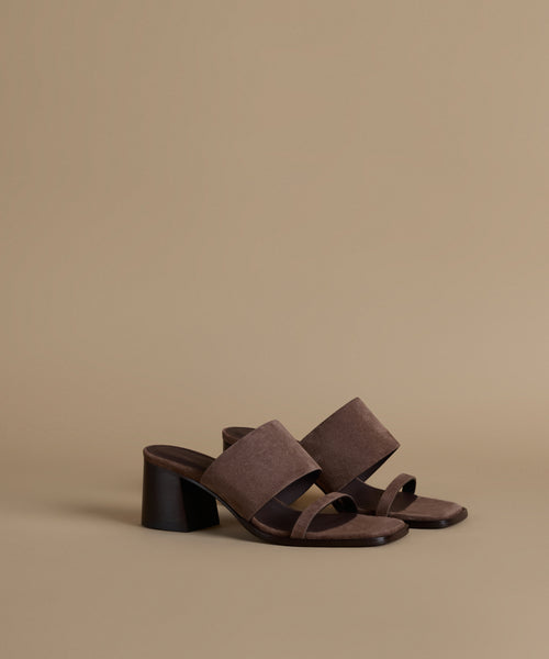 Brown sandals with a black block heel on a beige background