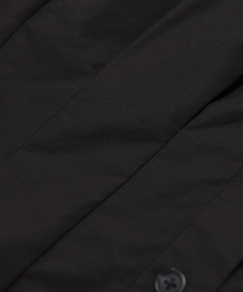 Close-up of the Lara Top in smooth, slightly matte Italian washed poplin, featuring visible stitching and a small button detail at the bottom right.