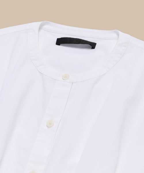 The Lara Top, made from Italian washed poplin with a button front and round neckline, is neatly folded and displayed on a beige background.