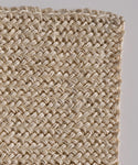 Close-up of the Laurel Bath Mat, a 100% fique ivory piece featuring natural beige fibers and a detailed textured pattern, with a gentle curve at the top left edge.