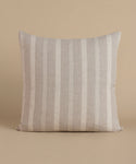 A cream and natural stripe pillow against a beige background.