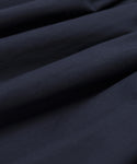 Close-up of dark navy blue fabric with soft folds and gentle shadows, highlighting the smooth, slightly textured surface of the Lauren Skirt.