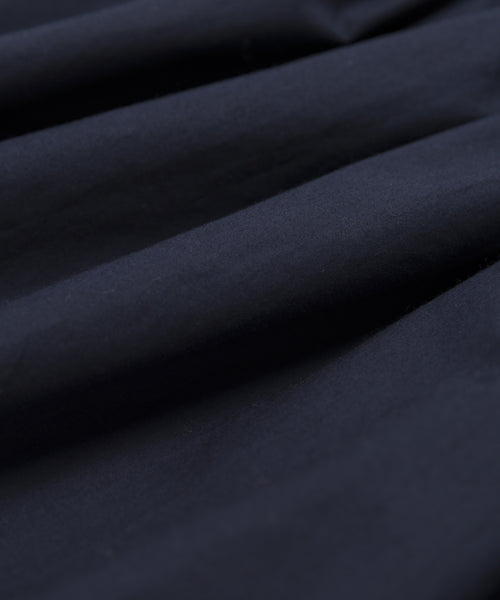 Close-up of dark navy blue fabric with soft folds and gentle shadows, highlighting the smooth, slightly textured surface of the Lauren Skirt.